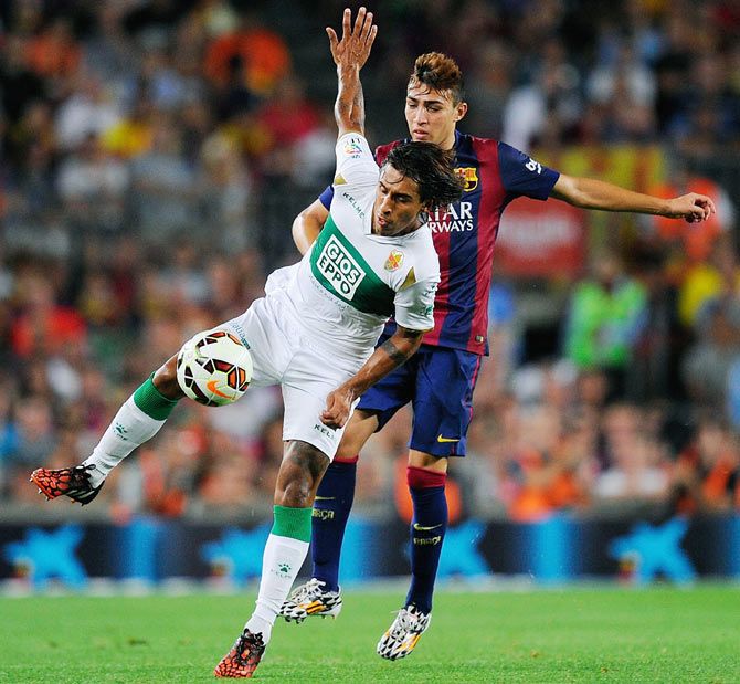 Damian Suarez (left) of Elche FC is challenged by Munir El Haddadi of FC Barcelona during their La Liga match on Sunday