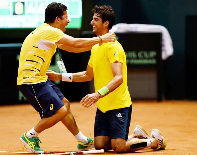 Thomaz Bellucci of Brazil (right) celebrates winning his play-off singles match against Roberto Bautista Agut of Spain on the World Group Play-off round of the Davis Cup at Ibirapuera Gymnasium in Sao Paolo on Sunday