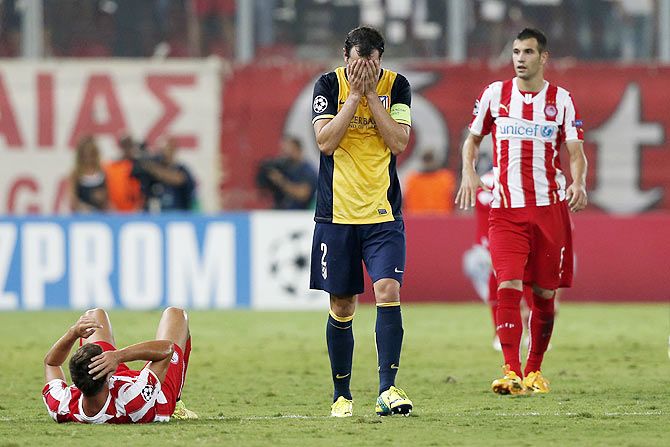 Atletico Madrid's Diego Godin (centre) reacts after he fouled Olympiakos' David Fuster (left) during their Champions League soccer match at Karaiskaki stadium
