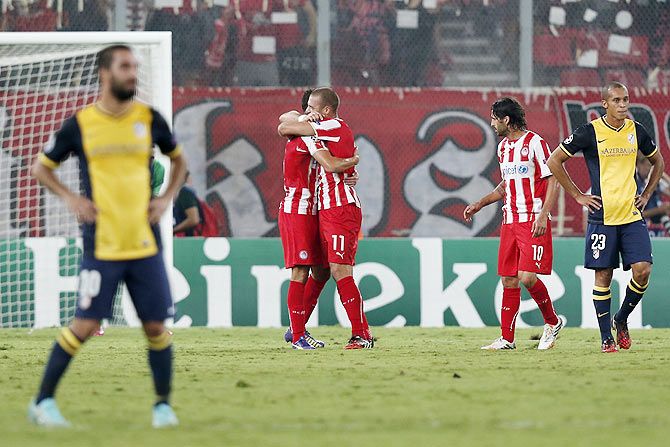 Olympiakos' Pajtim Kasami (3rd right) hugs scorer Ibrahim Afellay after scoring against Atletico Madrid during their Champions League soccer match