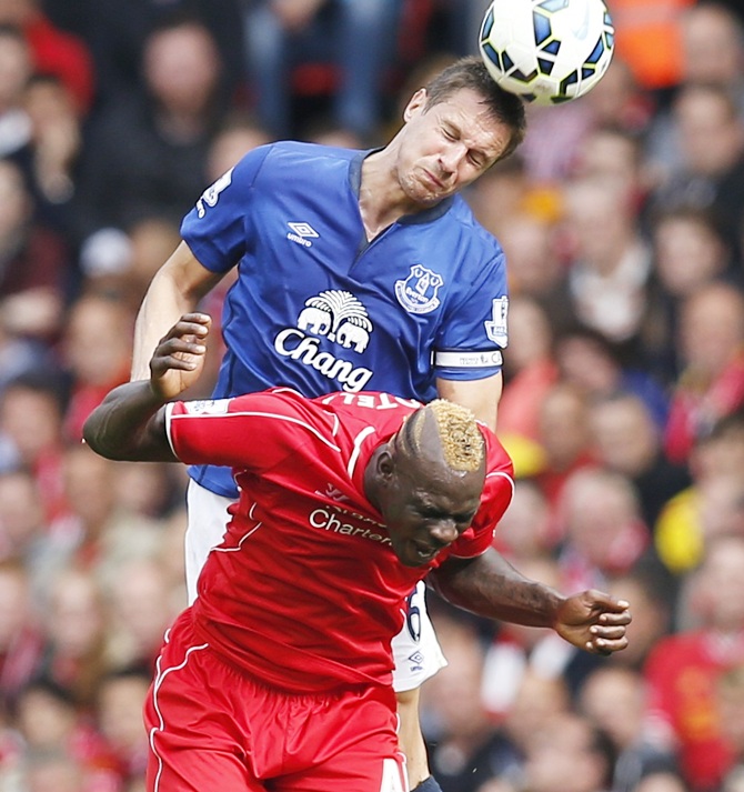 Liverpool's Mario Balotelli (bottom) challenges Everton's Phil Jagielka during their English Premier League match at Anfield