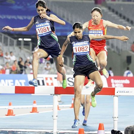 India's Lalita Babar and compatriot Sudha Singh lead Chinas Li Zhenzhu during the women's 3000 meters steeplechase final