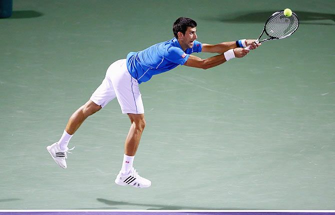 Novak Djokovic of Serbia stretches to play a backhand against John Isner of the United Staes in their Miami Open semi-final on Friday