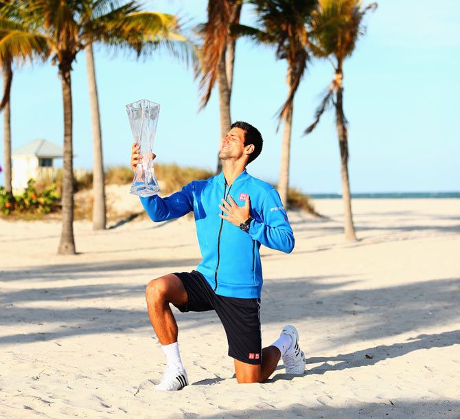 Serbia's Novak Djokovic poses on Crandon Park beach with the Butch Buchholz trophy after his three set victory against Great Britain's Andy Murray in the Miami Open final, in Key Biscayne, Florida, on Sunday