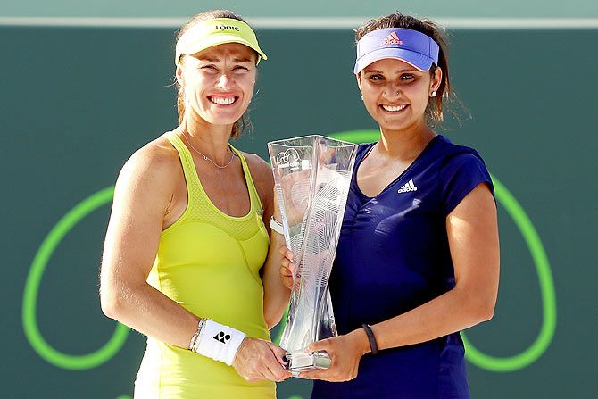 Martina Hingis of Switzerland and Sania Mirza of India pose with the Butch Buchholz Trophy after defeating Ekaterina Makarova and Elena Vesnina of Russia to win the Miami Open doubles title on Sunday