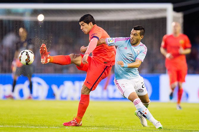 FC Barcelona's Luis Suarez is challenged by Celta Vigo's Gustavo Cabral