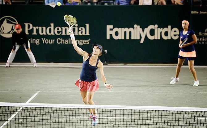 Martina Hingis plays a return as Sania Mirza looks on during the Family Circle Cup quarters
