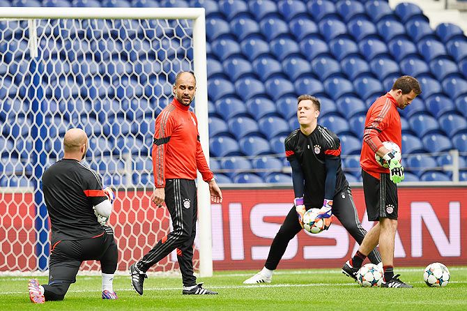 Bayern Munich's coach Pep Guardiola talks with goalkeeper Pepe Reina during a team training session