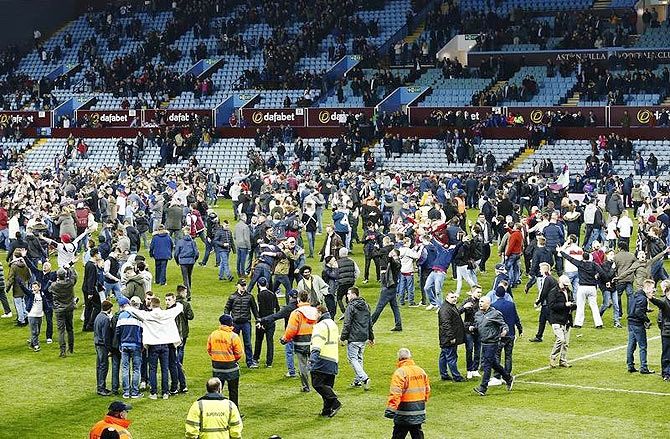 Aston Villa fans celebrate on the pitch after the match