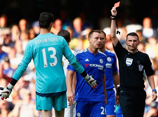 Chelsea's Thibaut Courtois, left, is shown the red card 
