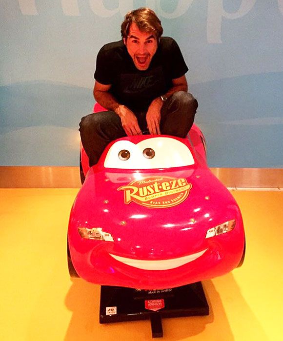Roger Federer sits on a toy car