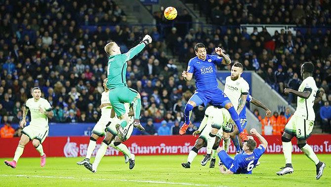 Leicester City's Leonardo Ulloa heads as Manchester City's 'keeper Joe Hart fists the ball out