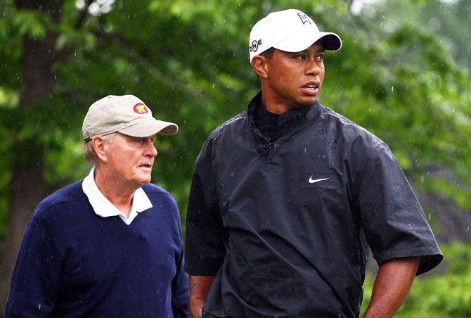 Tiger Woods watches a tee shot as Jack Nicklaus looks on