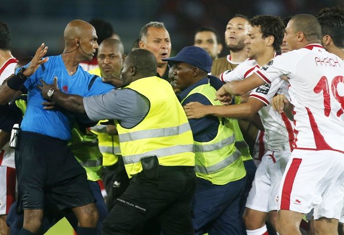 Referee Rajindraparsad Seechurn, left, is surrounded by security as Tunisia's players confront him after losing their quarter-final match 