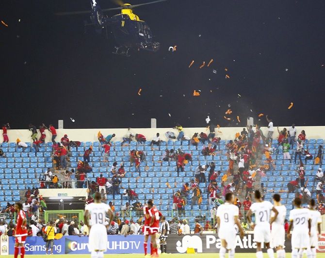 A police helicopter hovers over Equitorial Guinea fans as they throw objects 
