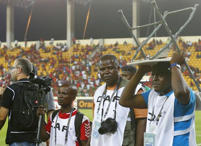 Members of the media take cover after Equatorial Guinea fans throw objects