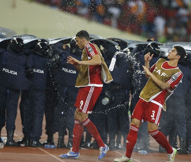 Equatorial Guinea's players dodge water bottles thrown by fans as police protect Ghana players