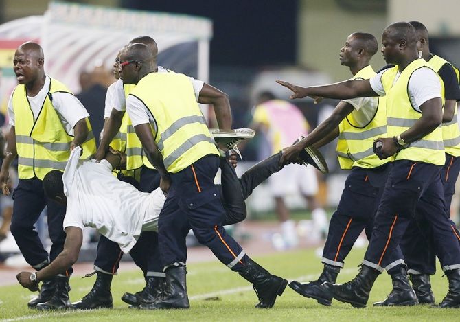 Security detain an Equatorial Guinea fan on the pitch after he tried to attack the referee 