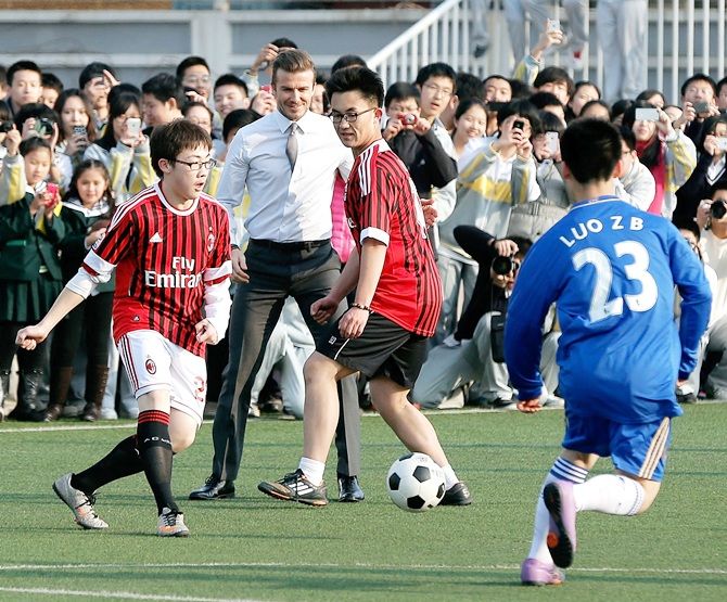 British football player David Beckham plays football with students during his visit to a   middle school in Beijing