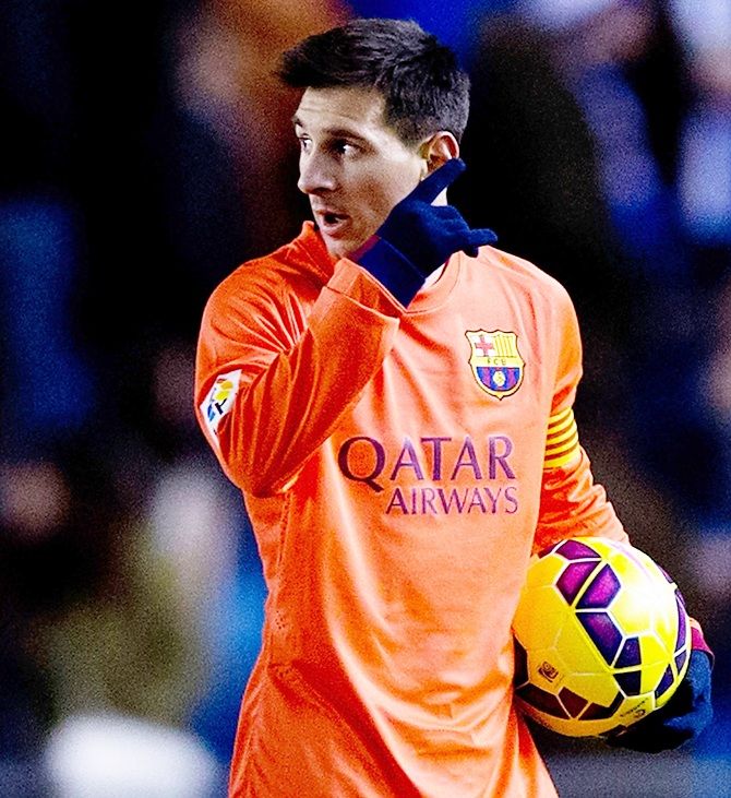 Lionel Messi of FC Barcelona points as he holds the ball as he leaves the pitch after his hat-trick