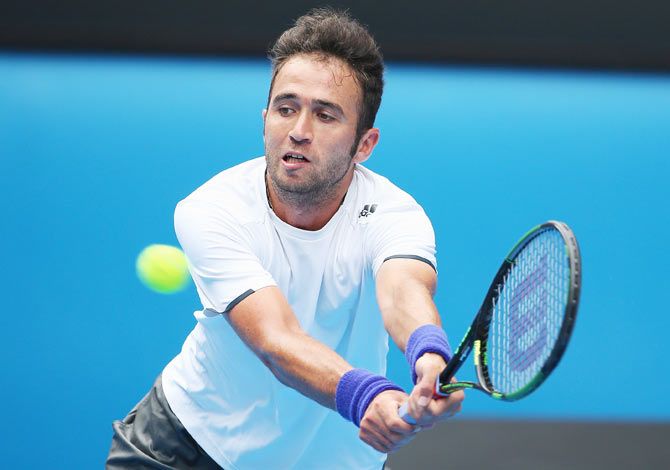 Marsel Ilhan plays a backhand in his first round match against Stanislas Wawrinka