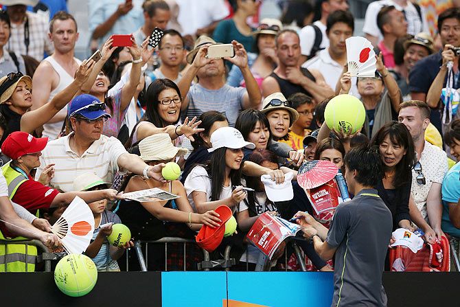 Kei Nishikori of Japan signs autographs for fans after winning his third round match against Steve Johnson of the United States