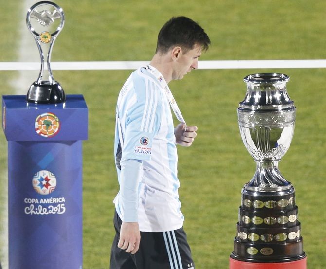 http://im.rediff.com/sports/2015/jul/05argentina1.jpg Argentina's Lionel Messi walks with his silver medal past the Copa America trophy
