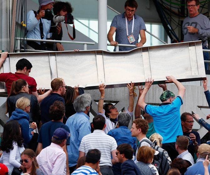 Spectators help lift a piece of the roof from Court Philippe Chatrier