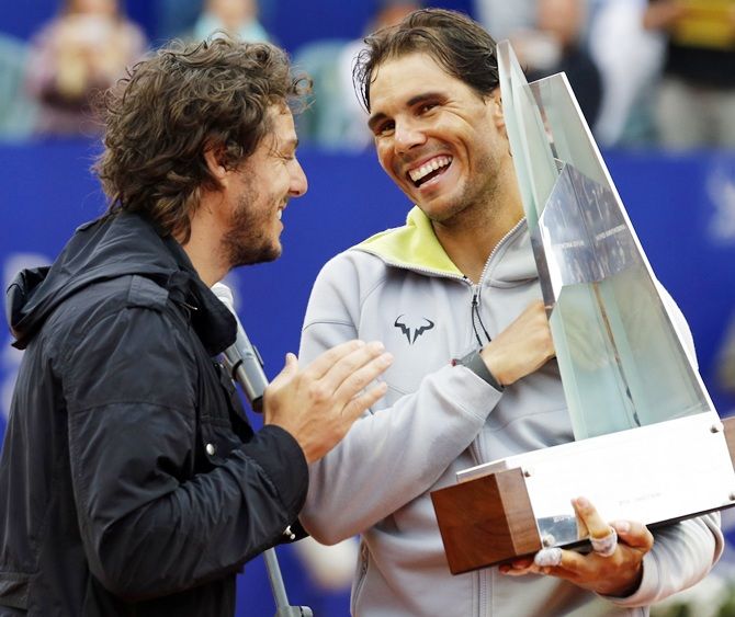 Spain's Rafael Nadal, right, receives the trophy from former Roland Garros champion Gaston Gaudio