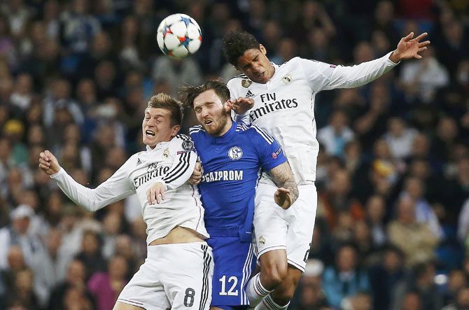 Real Madrid's Toni Kroos (left) and Raphael Varane (right) are involved in an aerial challenge with Schalke 04's Marco Hoger