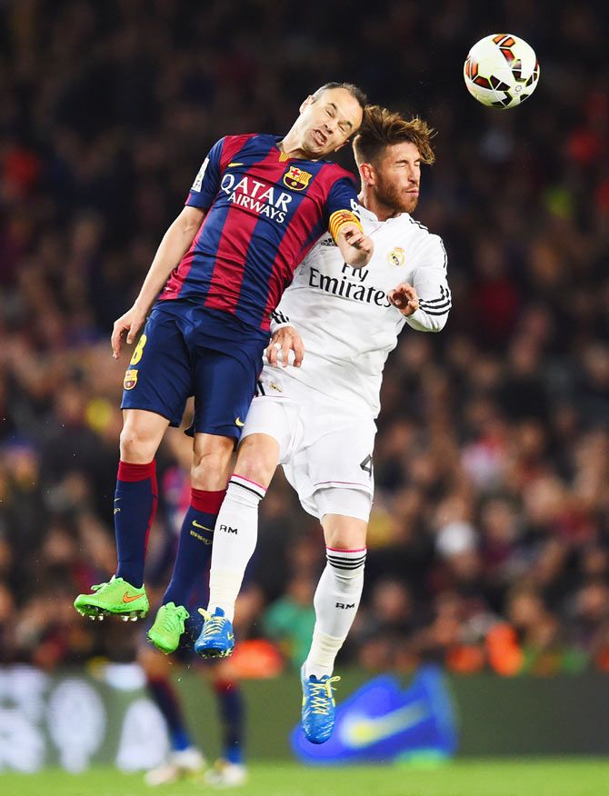 Barcelona's Andres Iniesta and Real Madrid's Sergio Ramos in an aerial challenge