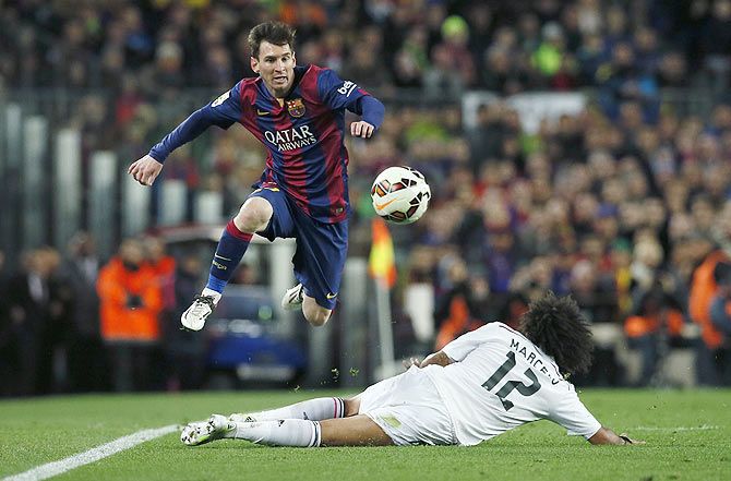 Barcelona's Lionel Messi (left) jumps as he as he intercepts a challenge by Real Madrid's Marcelo