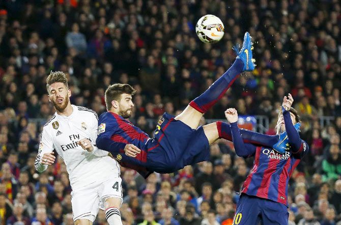 Barcelona's Gerard Pique (centre) is airborne as he attempts a bicycle kick past Real Madrid's Sergio Ramos (lef)