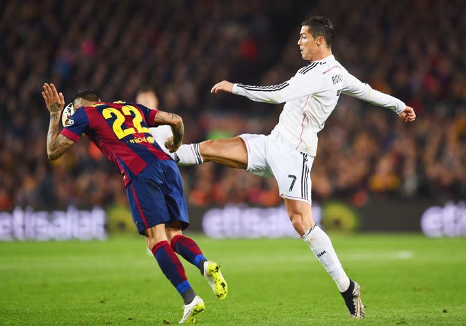 Real Madrid's Cristiano Ronaldo is challenged by Barca's Dani Alves