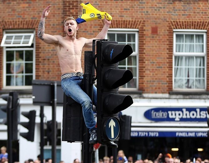 A Chelsea fan climbs on a set of traffic lights