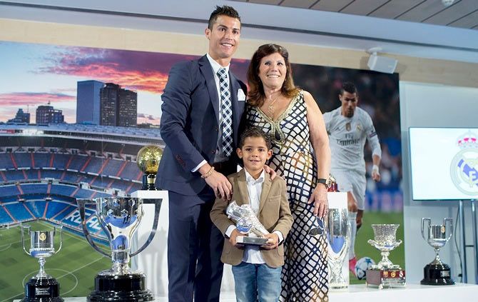 Cristiano Ronaldo poses for a picture with his trophy as all-time top scorer of Real Madrid CF with his son Cristiano Ronald JR and his mother Maria Dolores dos Santos at Honour box-seat of Santiago Bernabeu Stadium on October 2