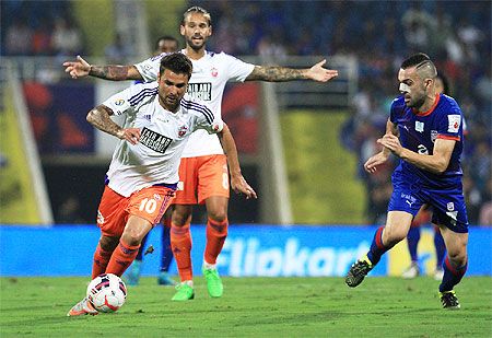FC Pune City's Adrian_Mutu charges ahead with the ball as Mumbai City FC's Cristian Bustos vies for possession