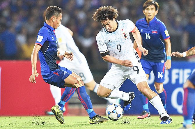 Japan's Shinji Okazaki (right) competes for the ball against his Cambodian opponent during their 2018 FIFA World Cup Qualifier in Phnom Penh, Cambodia, on Tuesday