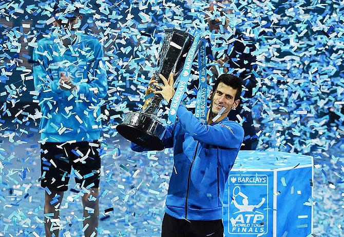 Serbia's Novak Djokovic celebrates with the trophy after winning the Barclays ATP World Tour Finals against Switzerland's Roger Federer at the 02 Arena in London on Sunday