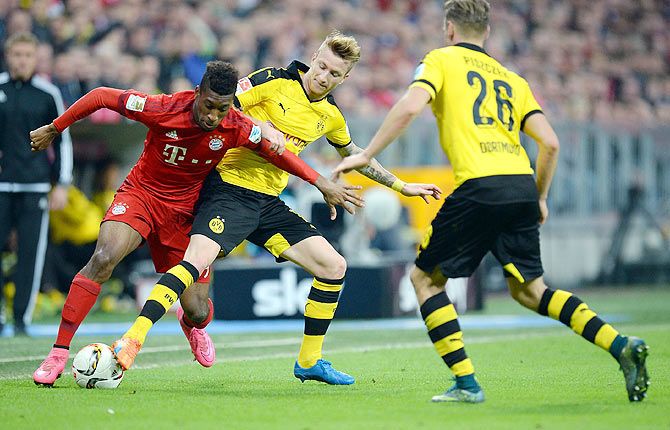 Bayern's Kingsley Coman (left) competes with Dortmund's Marco Reus as they vie for possession