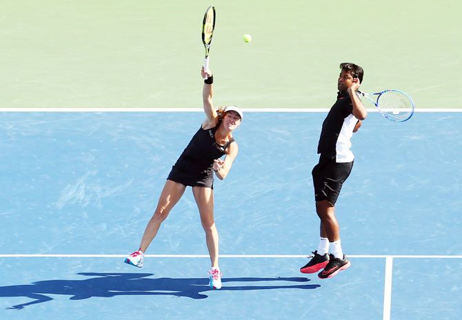 Switzerland's Martina Hingis plays a return as India's Leander Paes moves out of way during their US Open mixed-doubles final against USA's Bethanie Mattek-Sands and Sam Querrey