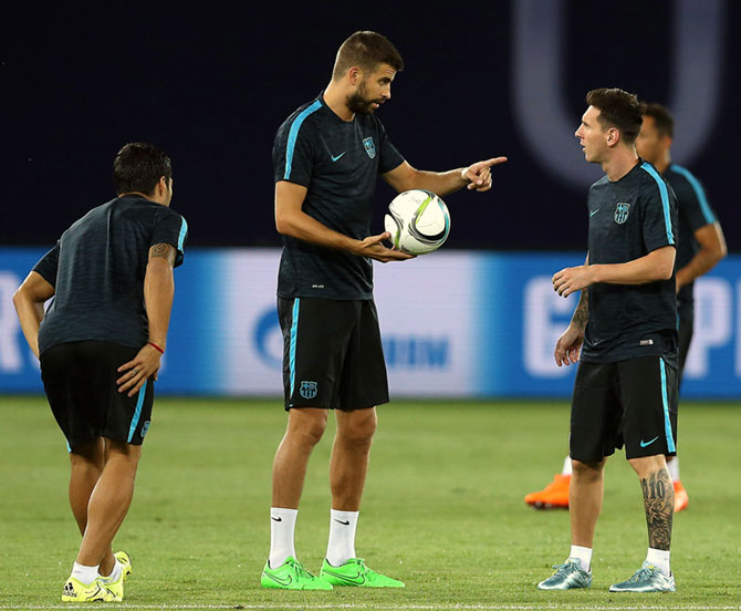 Gerard Pique (center) of Barcelona makes a point to team-mate Lionel Messi 