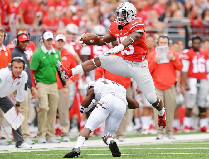 Ezekiel Elliott of the Ohio State Buckeyes leaps over Darius Phillips of the Western Michigan Broncos for a first down gain in the second quarter in their American football college league at Ohio Stadium in Columbus, Ohio, on Saturday