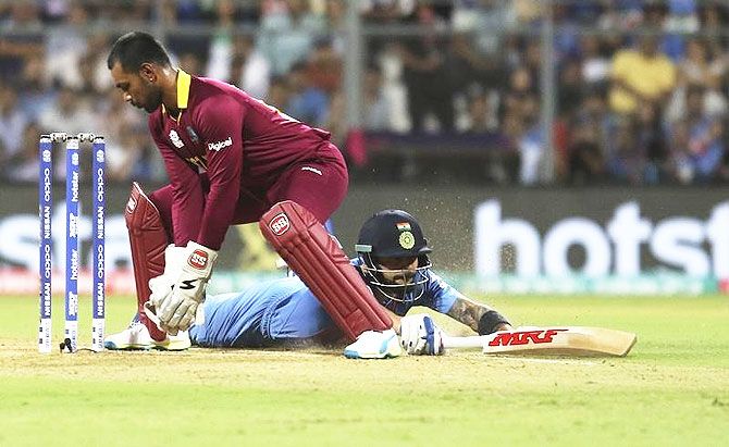 Virat Kohli (right) dives successfully to make his crease past West Indies wicketkeeper Denesh Ramdin during the World Twenty20 semi-final at the Wankhede in Mumbai on Thursday, March 31