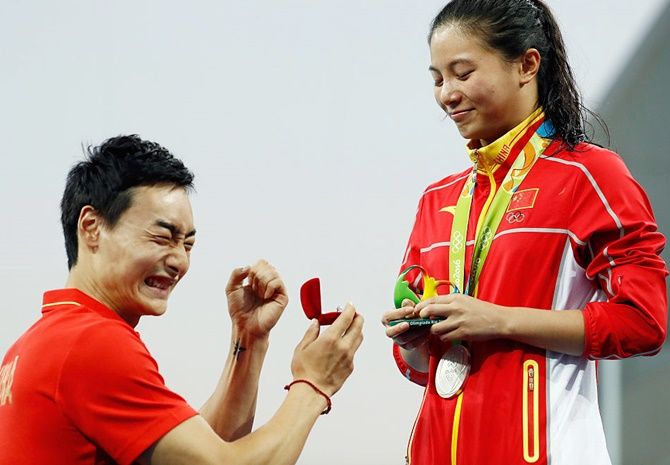 Chinese diver Qin Kai proposes to silver medalist He Zi of China on the podium during the medal ceremony for the Women's Diving 3m Springboard Final on August 14
