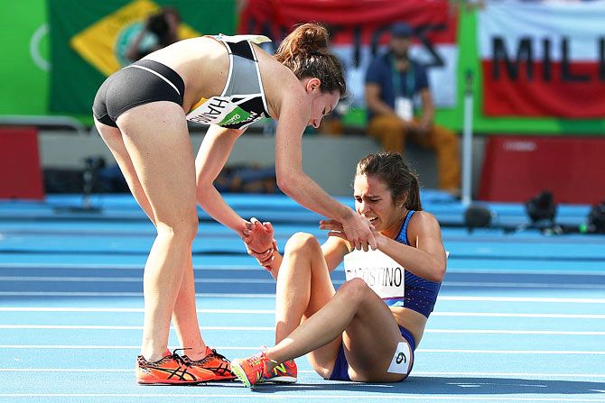 Abbey D'Agostino of the United States (right) is assisted by Nikki Hamblin of New Zealand after they collided during the Women's 5000m Round 1 - Heat 2 at the Olympic Stadium on August 16