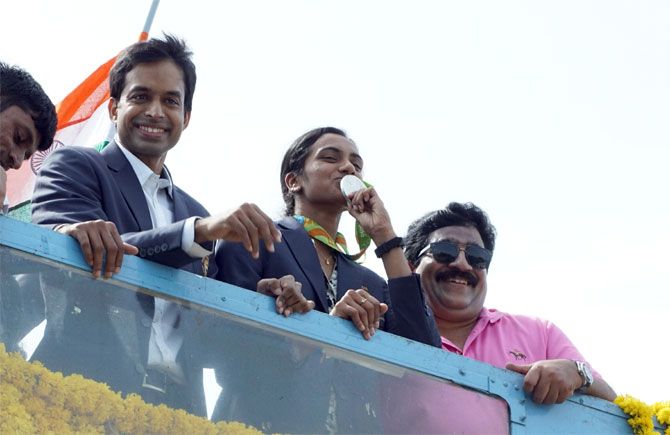 Rio Olympics silver medallist PV Sindhu and coach P Gopichand get a rousing reception atop an open-air bus in Hyderabad on her return from the Rio Games on August 22
