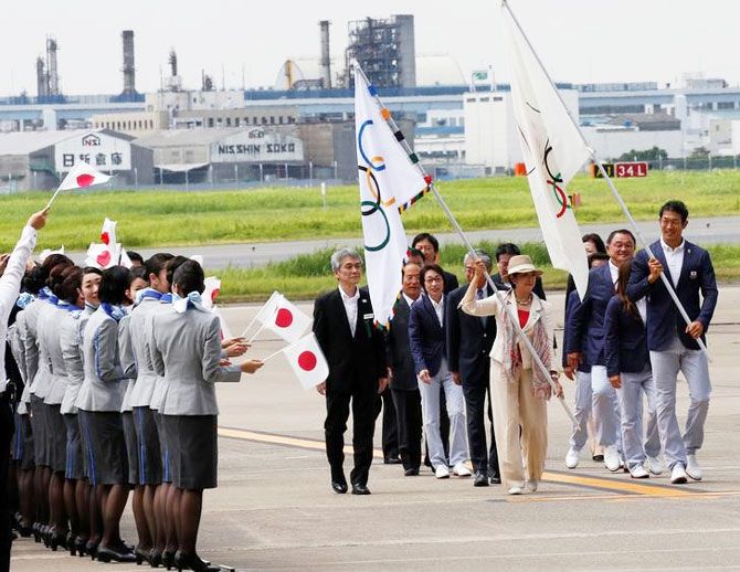 Tokyo governor Yuriko Koike (left) and Japan's Olympic team's sub-captain Keisuke Ushiro carry the Olympic flag (left) and JOC flag during a ceremony to mark the arrival of the Olympic flag at Haneda airport in Tokyo, Japan, on Wednesday