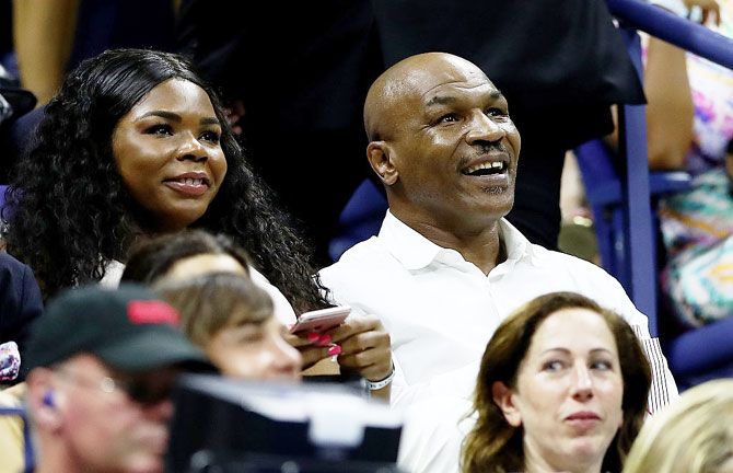 Former boxing heavyweight champion Mike Tyson (right) watches the first round match between Novak Djokovic and Jerzy Janowicz