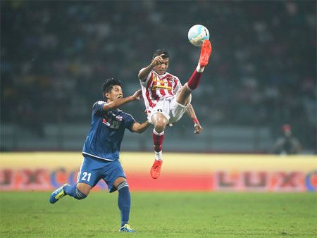 Atletico de Kolkata's Keegan Pereira clears the ball as he is challenged by a FC Pune City player during their ISL match in Kolkata on Friday